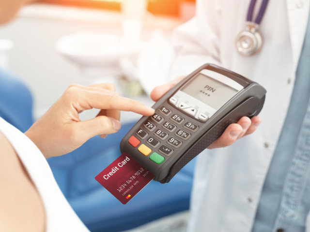 Doctor is holding payment terminal in hands
