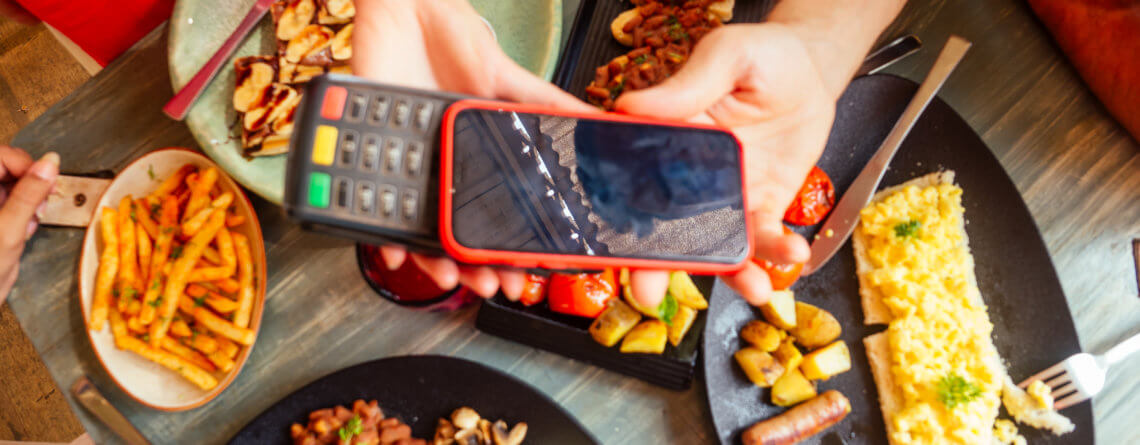 indian man paying in restaurant by credit card app on smartphone reader