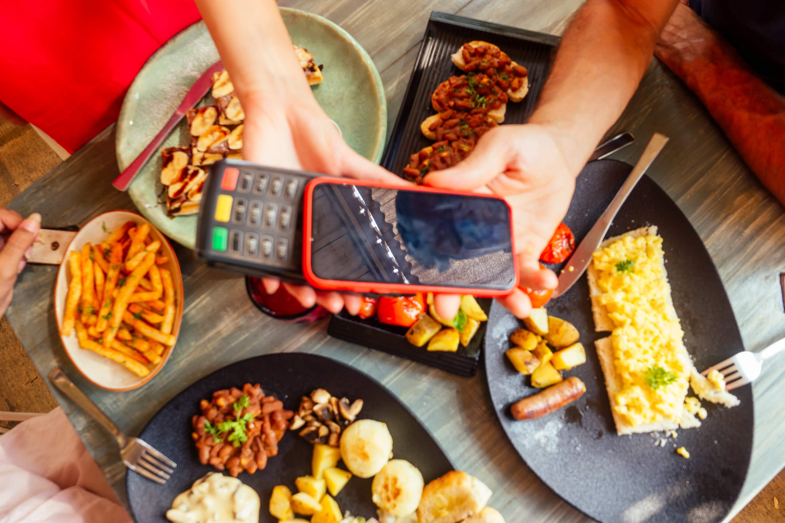 indian man paying in restaurant by credit card app on smartphone reader